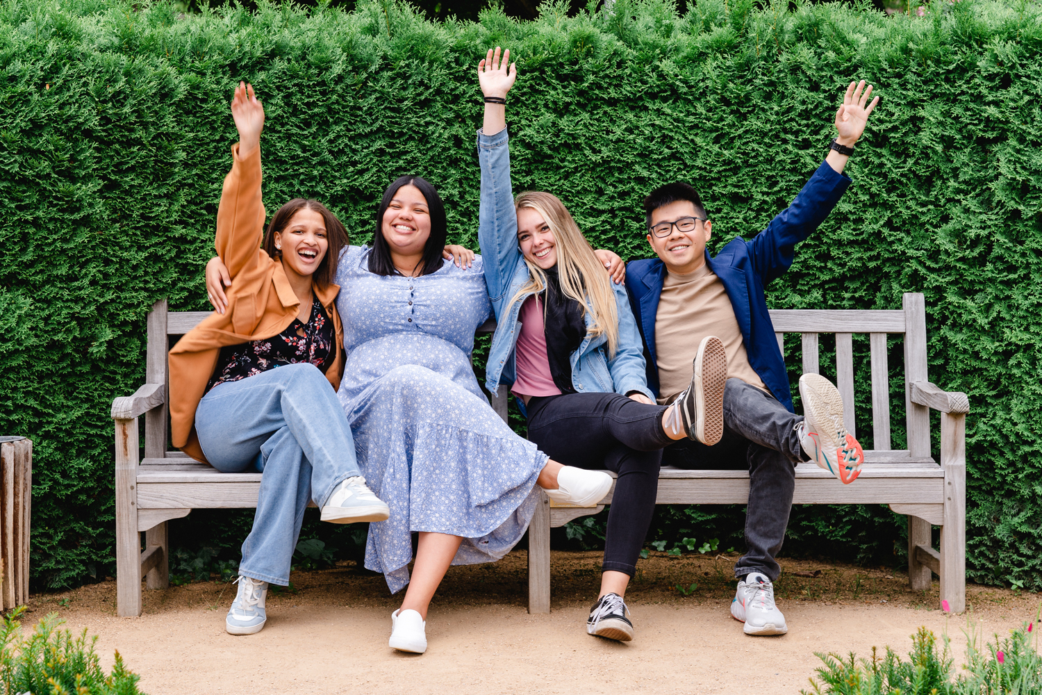 Four students sit on a bench and cheer happily.