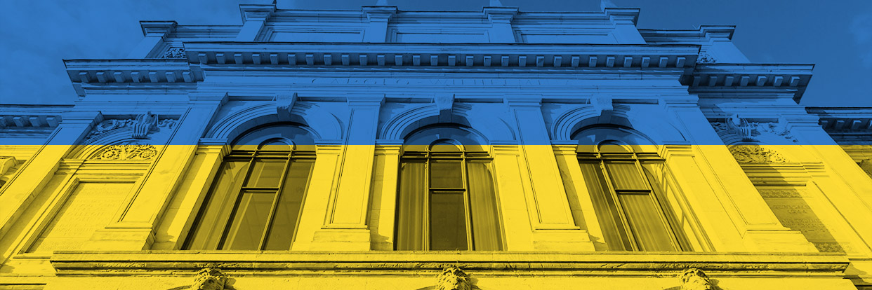 Photo of the old building at TU Braunschweig in the colours blue-yellow with the lettering "We stand with Ukraine". 