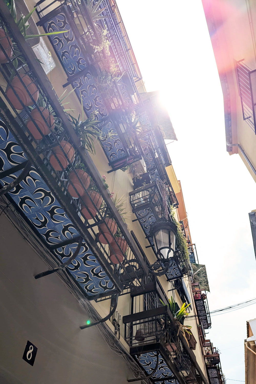 Ein sonniger Blick auf bunt bemalte Balkone eines Mehrfamilienhauses in Valencia von unten.