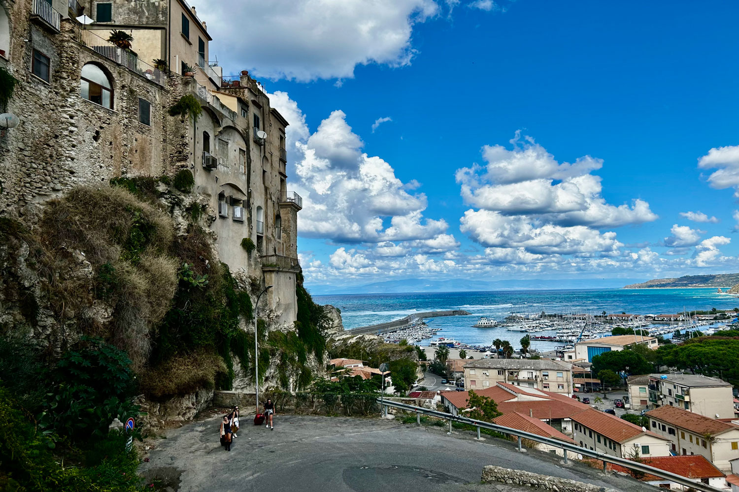 Blick auf eine italienische Stadt und auf das historische Hafenviertel. Im Hintergrund ist das Meer zu sehen.