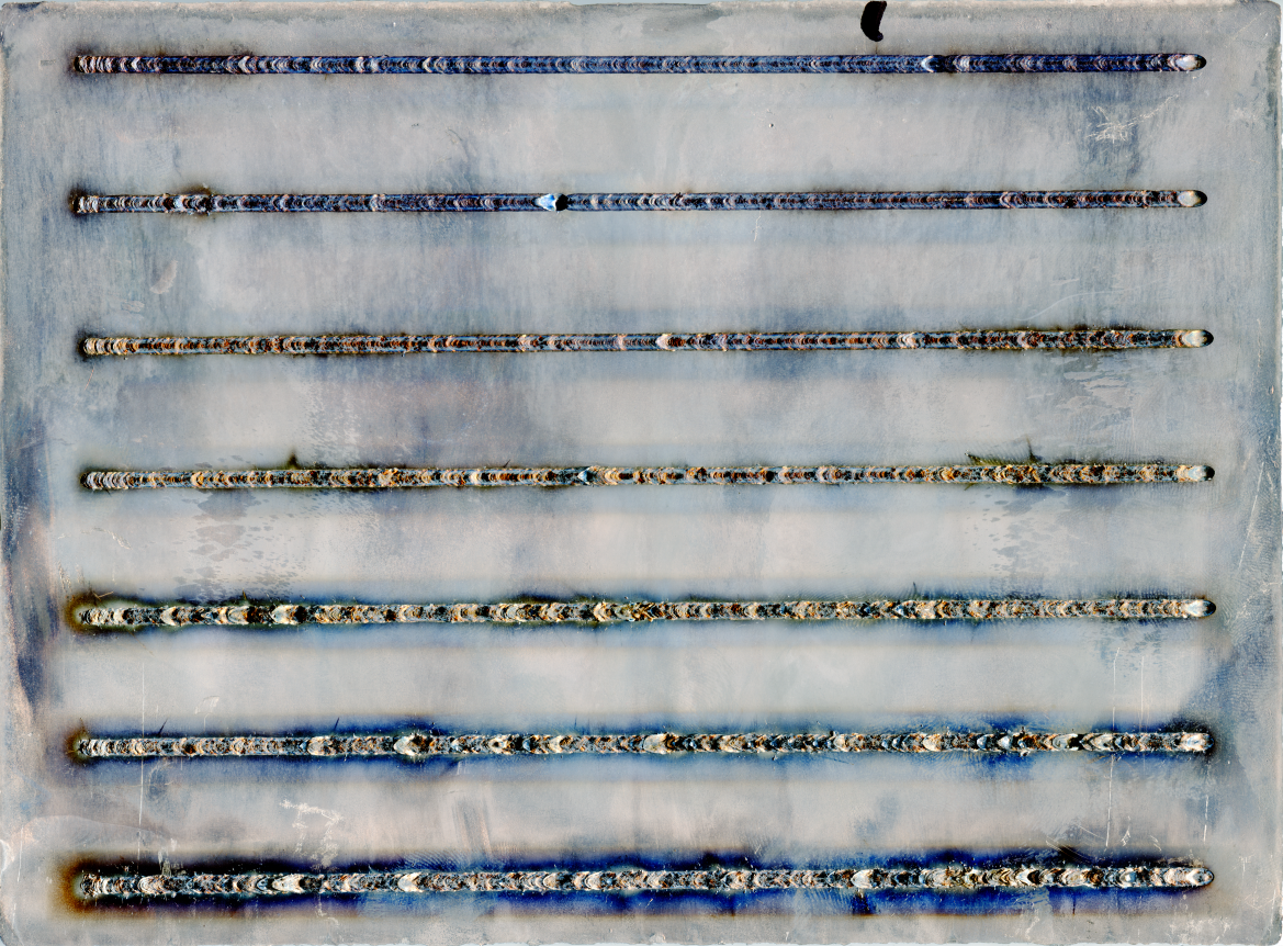 Das Bild zeigt eine Aluminium-Druckgussplatte mit 7 horizontalen Schweißnähten. Die Schweißnähte werden mit steigender Entfernung zur unteren Kante der Platte sauberer und gleichmäßiger.