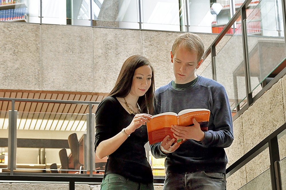 Zwei Studierende schauen gemeinsam in ein Buch