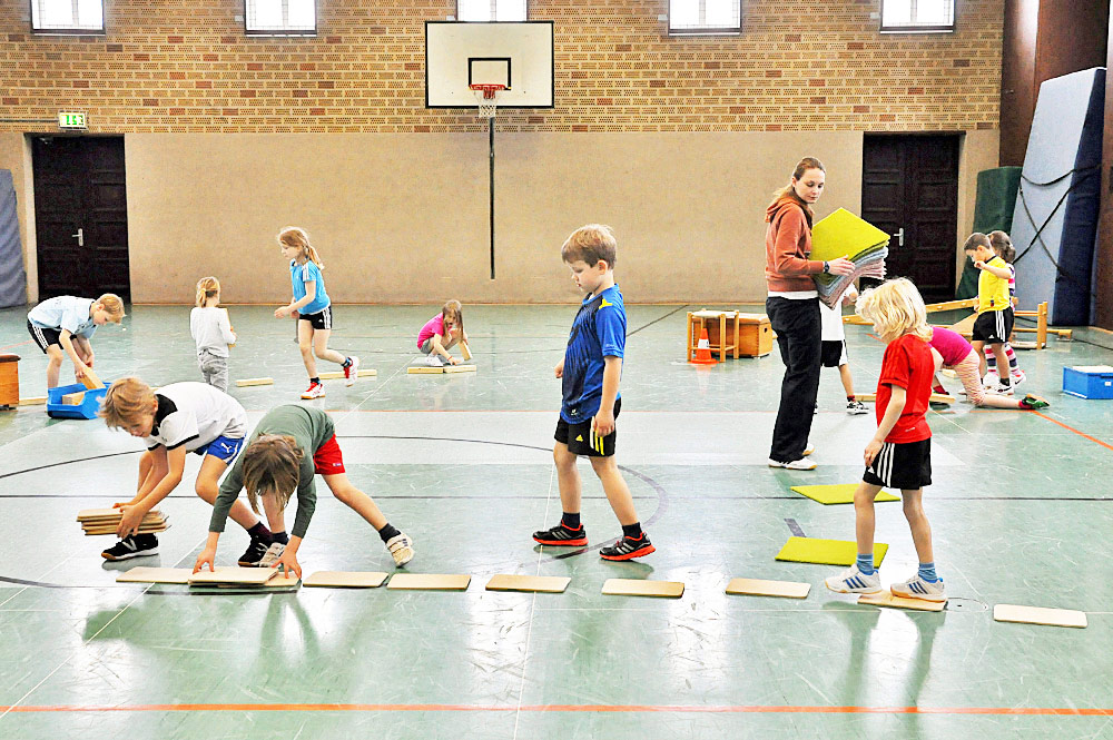 Eine Studentin bereitet mit Schulkindern ein Spiel in der Sporthalle vor
