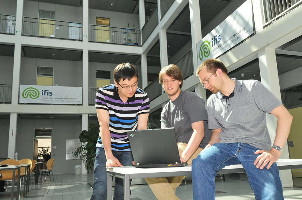 Drei Studierende vor einem Laptop im Institut