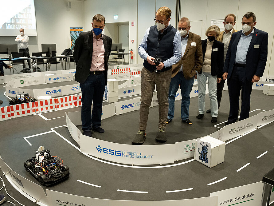 Stefan Muhle (Mitte) steuert das Modellfahrzeug unter Anleitung von Prof. Dr. Andreas Rausch (links) durch den Parcours.