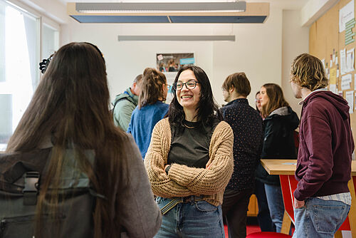 Studierende sprechen miteinander, Frau lächelt