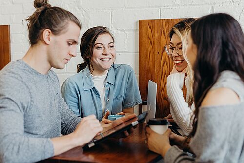 A group of young people sits around the table and exchanges ideas.