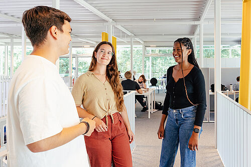 Drei Studierende stehen im Studierendenhaus der TU Braunschweig und unterhalten sich.
