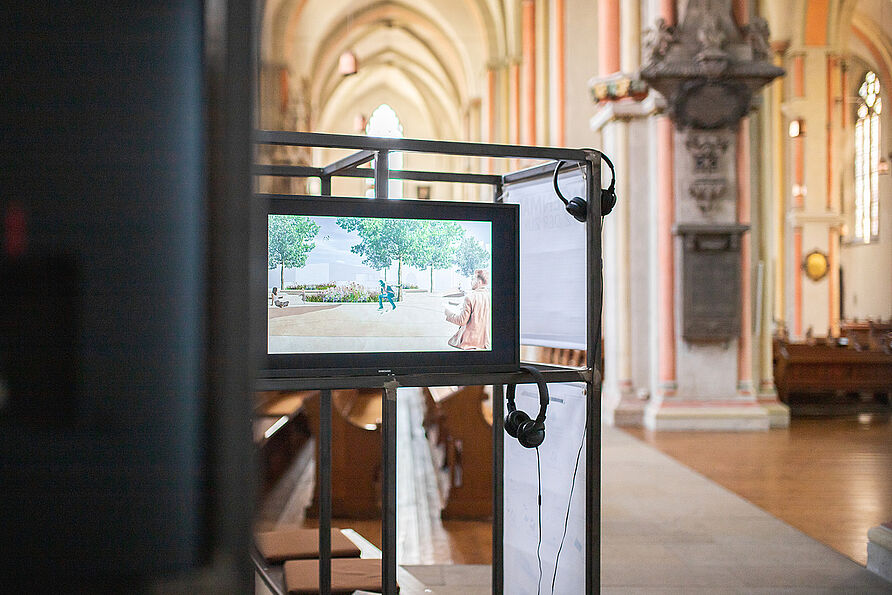 Auf Bildschirmen können sich Besucher:innen der Ausstellung die Entwürfe der Studierenden ansehen. 