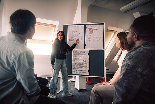Studentin präsentiert Ergebnisse an der Pinnwand