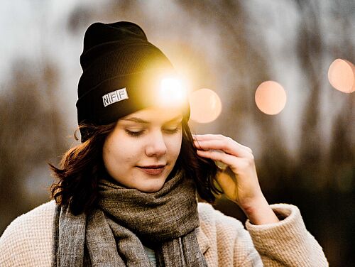 Junge Frau mit schwarzer NFF-Mütze mit LED-Leuchte