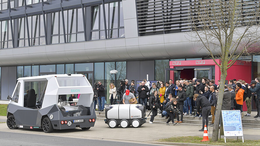 Abschlussveranstaltung im LogiSmile-Projekt am 22. März 2024 am NFF: RAION und ONA stehen vor dem NFF-Gebäude, die Gäste schauen zu.