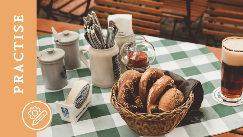 A set table with a tablecloth, silverware, pretzels, and a beer.