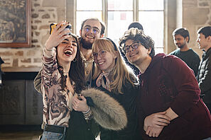 Mehrere Studierende machen beim offiziellen Empfang der Stadt Braunschweig ein Selfie und lachen in die Kamera. 