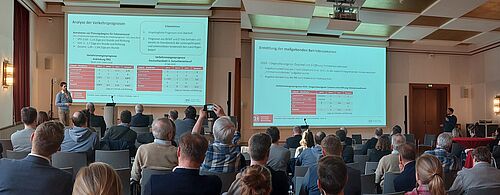 Zusammenschnitt zweier Bilder. Zu sehen sind die Vortragenden links und rechts im Bidl. Der Vortragsraum strahlt eine warme Atmosphäre aus.