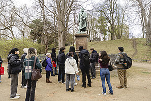Studierende betrachten während der Stadtführung eine Statue.