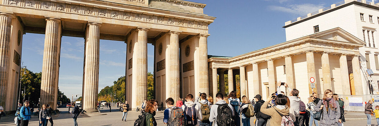 Eine Gruppe Studierender steht vor dem Brandenburger Tor in Berlin. 