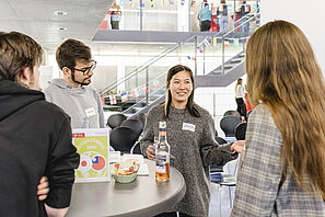 Studierende tauschen sich während der Outgoing-Messe an Stehtischen über ihre Auslandserfahrungen aus.