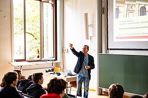 Ein Vortragender steht in einem Hörsaal und hält einen Vortrag vor Studieninteressierten