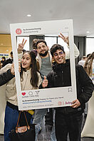 Drei Studierende posieren beim Welcome Week-Kick off mit einem Instagram-Fotorahmen für ein Foto.