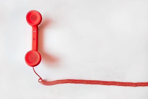 Symbolbild: Roter Telefonhörer mit Schnur 