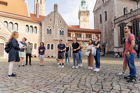 Eine Gruppe von Menschen bei einer Stadtführung auf dem Domplatz in Braunschweig