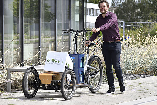 Junger Mann schieb ein Lastenfahrrad vor dem NFF-Gebäude