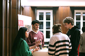 Conference participants stand together at a bar table and chat.