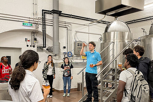 Students stand in a brewery cellar during a tour.
