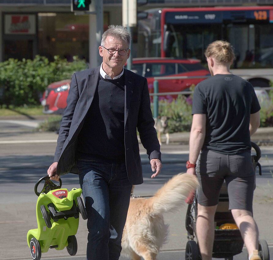 Prof. Bernhard Friedrich hat an einer Kreuzung ein Bobbycar in der Hand.