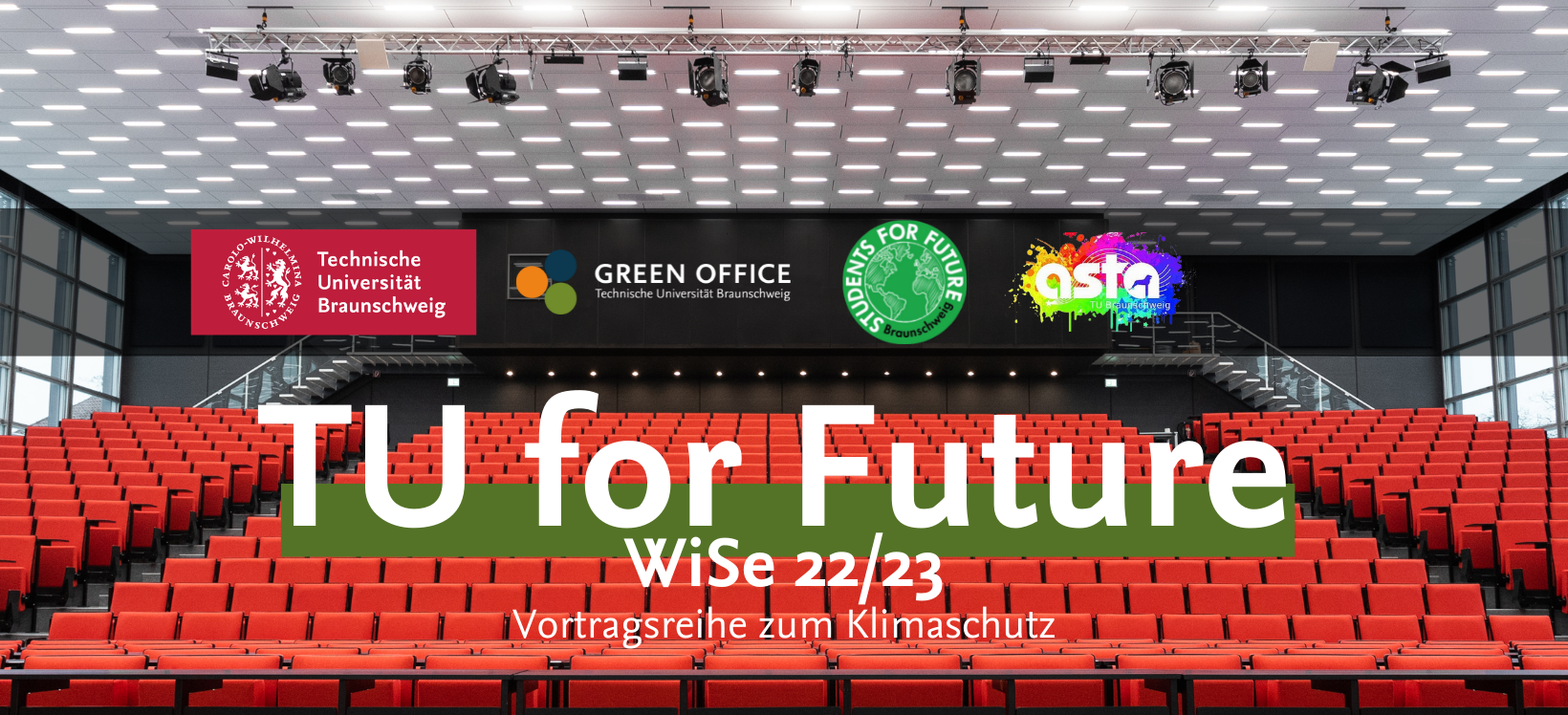 Es handelt sich um ein Werbungs-Banner der TU for Future Vorlesungsreihe. Zu sehen ist dabei das volle Audimax. Davor steht in großer Schrift "TU for Future". Außerdem sind die Logos von der TU Braunschweig, den Students for Future, dem Green Office und dem AStA dort zu sehen.