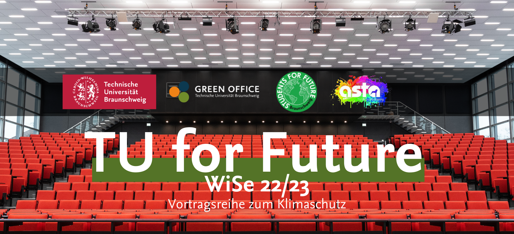 Es handelt sich um ein Werbungs-Banner der TU for Future Vorlesungsreihe. Zu sehen ist dabei das volle Audimax. Davor steht in großer Schrift "TU for Future". Außerdem sind die Logos von der TU Braunschweig, den Students for Future, dem Green Office und dem AStA dort zu sehen.