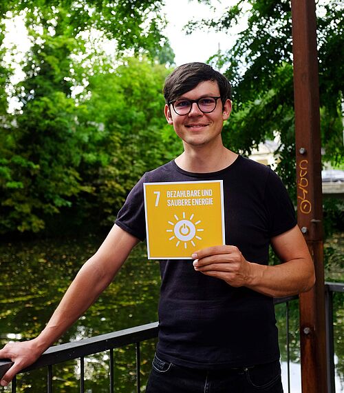 Malte Schäfer hält die Karte vom 7. SDG.