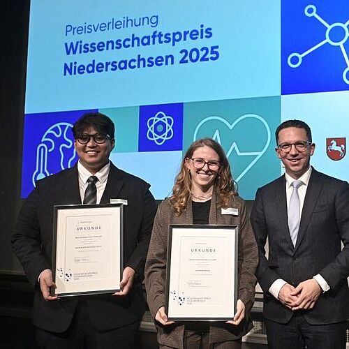 Studierenden Ahmad Iqbal Bin Mohd Shahir Shamsir und Luca Madita mit Wissenschaftsminister Falko Mohrs