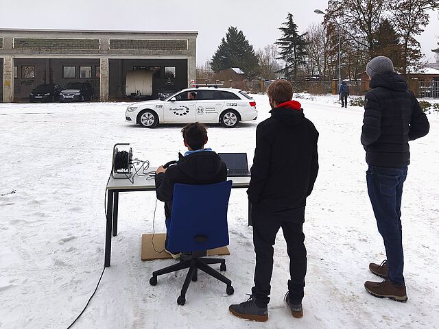 Schüler lenkt ein Auto mit einem Lenkrad ohne im Auto zu sitzen