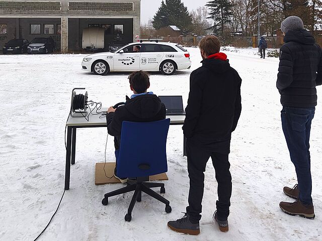 Schüler lenkt ein Auto mit einem Lenkrad ohne im Auto zu sitzen
