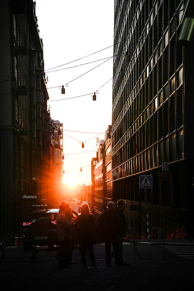 Eine Straße in Stockholm. Am Horizont bricht die Sonne durch. 