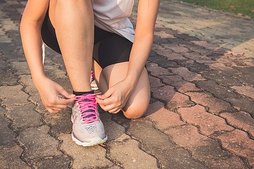 Eine Person schnürt sich Ihren Sportschuh