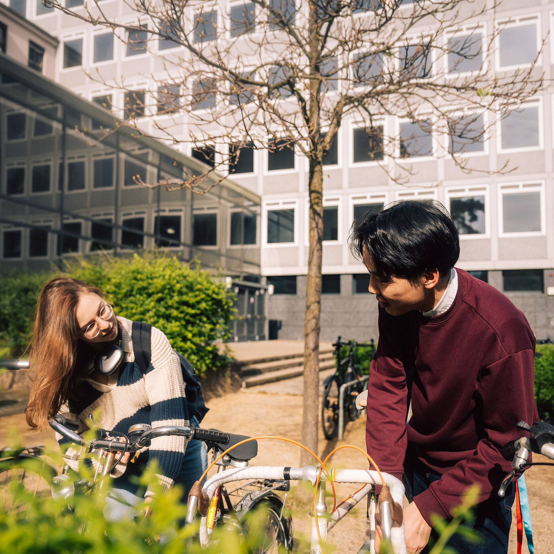 Two students of TU Braunschweig talking to eachother whilst unlocking their bikes