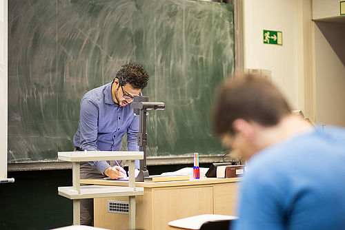 Ein Lehrender schreibt etwas auf einem OHP