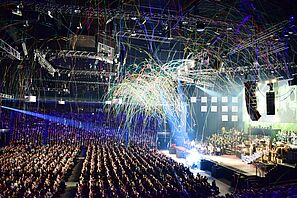 Streamers fly through a large and well-attended event hall.