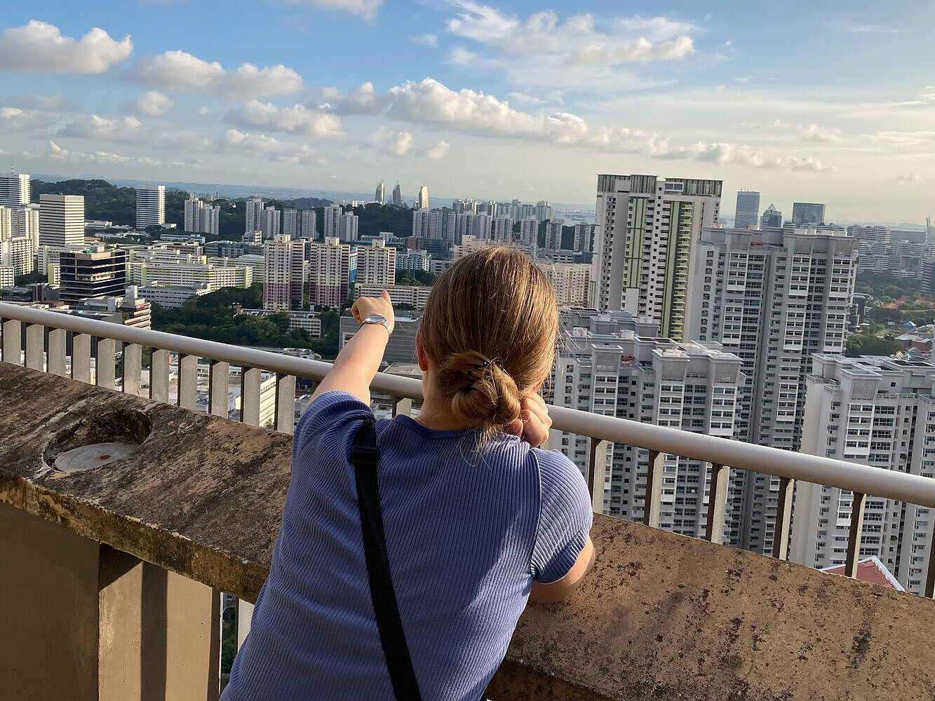Die Studentin steht uaf einem Wohngebäude in Queenstown und genießt den Ausblick über die Stadt Singapur. 