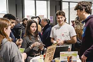 Studierende tauschen sich beim Kick Off der Welcome Week an einem Infotisch mit Berater*innen aus. 