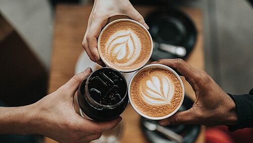 Eine Gruppe von Leuten, die ihre Kaffeetassen zusammenhalten