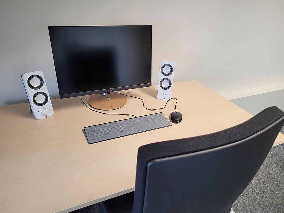 Computer monitor, keyboard, speakers, and mouse on a table.