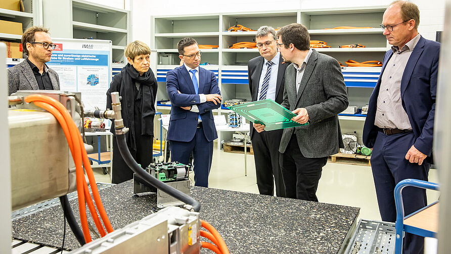 Besuch Nds. WIssenschaftsminister Falco Mohrs am 20.11.2023 im NFF: Besichtigung der E-Prüfstände mit Erläuterung an Bauteil.