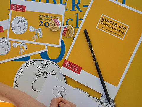Stift und Heft mit Logo der Kinder-Uni