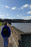 Eine Studentin geht in Conwy, einer walisischen Stadt, spazieren. Im Hintergrund ist die historische Burg der Stadt zu erkennen.