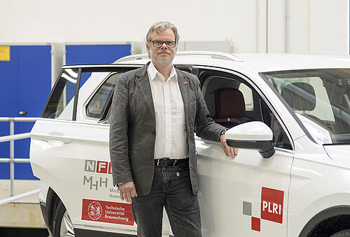 Prof. Deserno neben seinem Forschungsfahrzeug im NFF-Technikum.