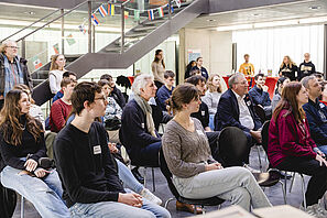 Besucher*innen der Messe hören einem Vortrag zu.